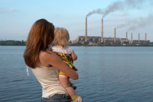 "care future" concept. Young mother with her kids are looking at the chimney-stalks polluting an air